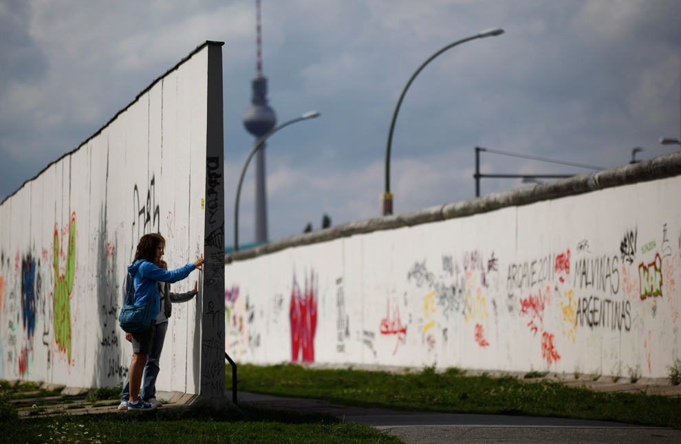 Туристы осматривают часть стены разрисованную граффити
