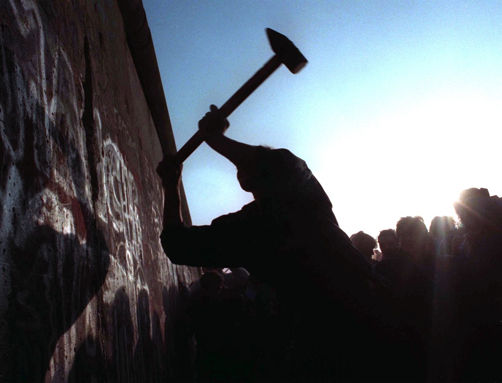 Человек разбивает молотом Берлинскую стену