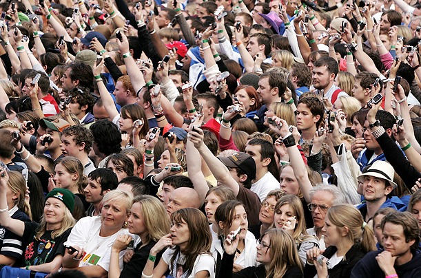  Фанаты на концерте в Эдинбурге размахивают своими телефонами.  