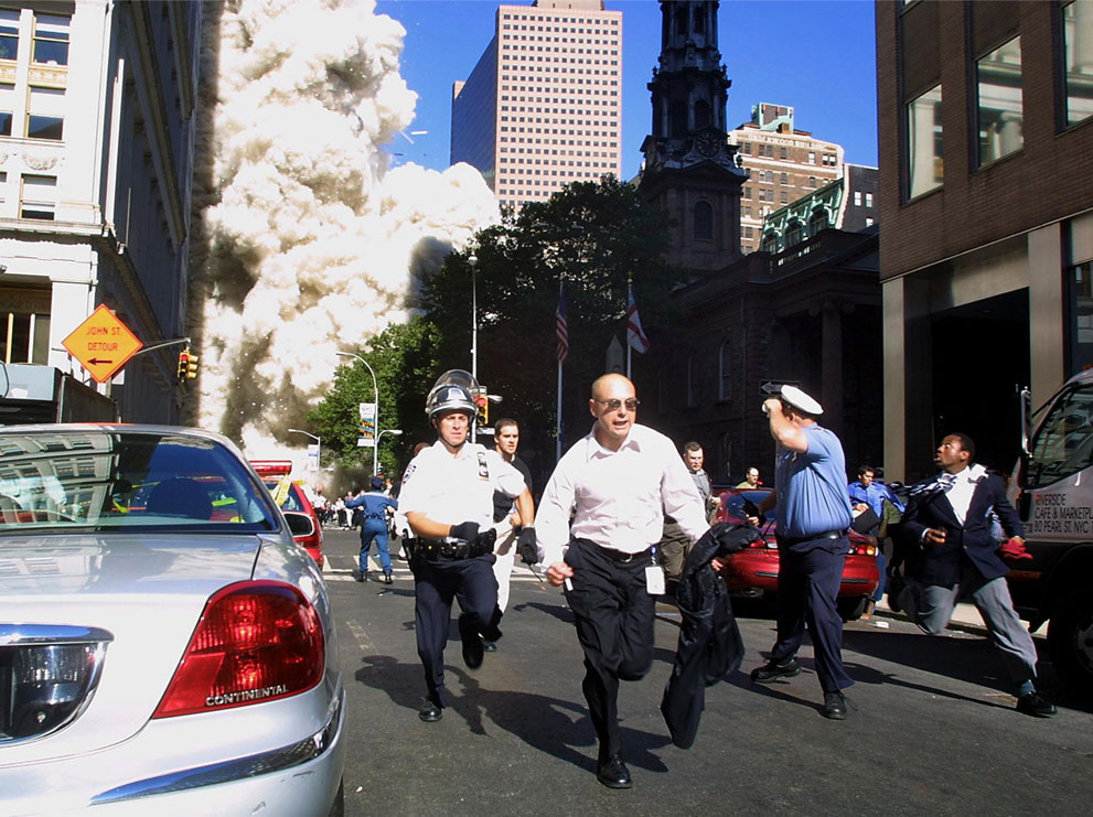 Полиция и пешеходы бегут от обрушившегося Всемирного торгового центра.