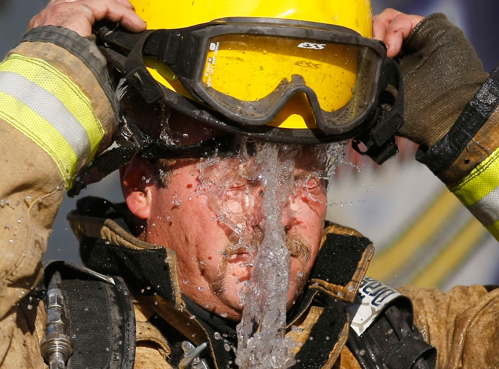 Пожарный выливает на себя воду, во время тушения пожара. Фениксе, штат Аризона