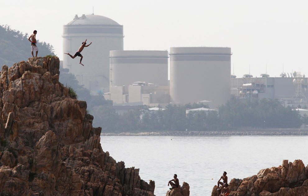 Мальчик ныряет со скалы возле атомной электростанции. префектура Фукуи, Япония