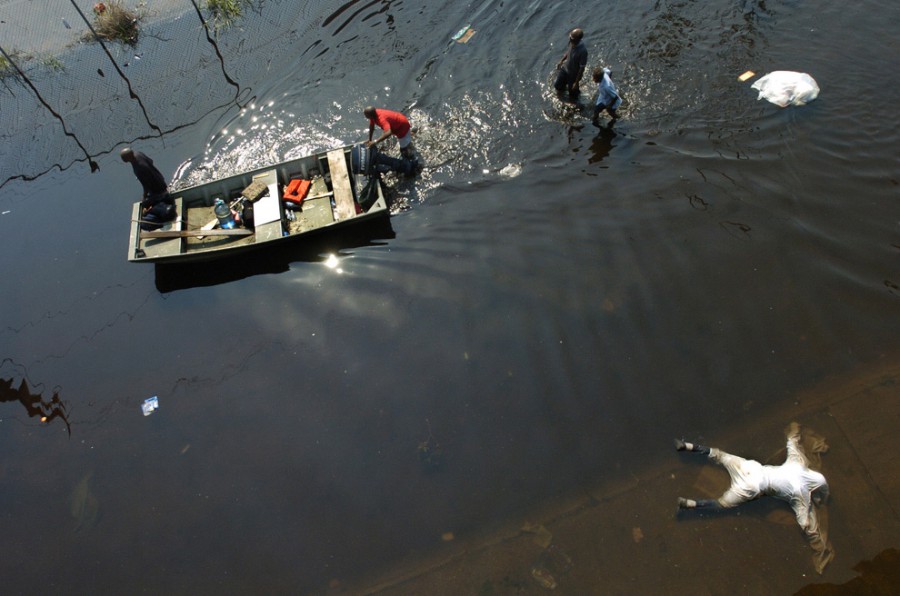 Труп плавает в  воде, люди  используют лодку, чтобы помочь жертвам урагана Катрина   в Новом Орлеане