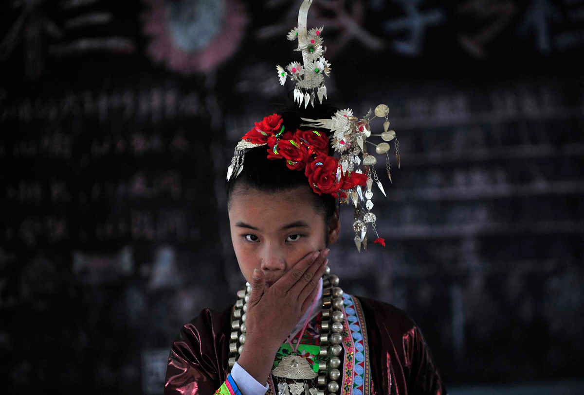 Девушка народности дун, в национальном костюме, готовится принять участие в исполнении Большого хора Кам, в память о 18 молодых пар, которые пожертвовали собой ради любви, согласно местной легенде. 