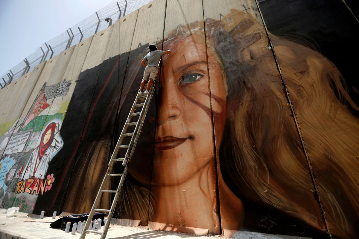 Итальянский художник работает над фреской на стене в Вифлееме, изображающей заключенную в тюрьму палестинскую девушку-подростка Ахед Тамими (Ahed Tamimi), Западный берег реки Иордан, 25 июля 2018 года.